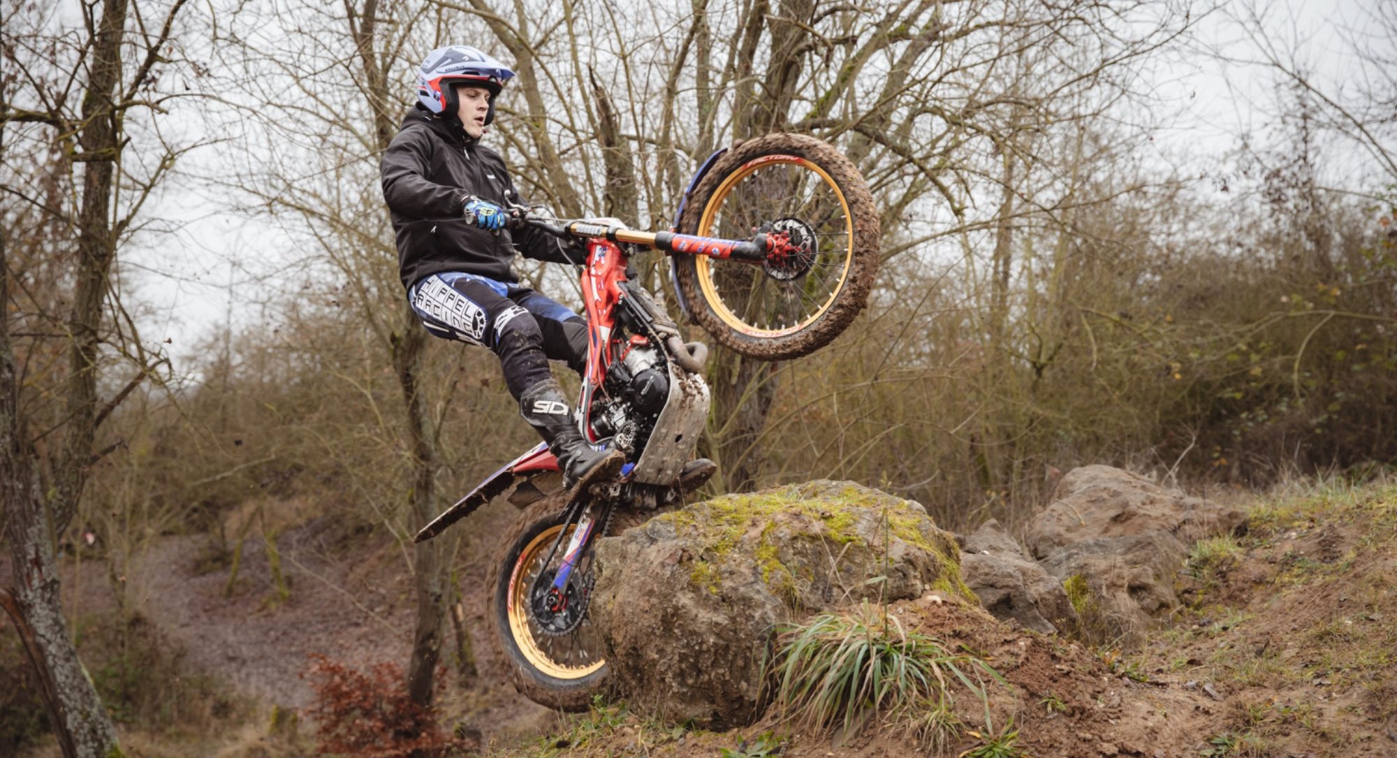 Person auf einem Trial-Motorrad, der über einen Stein springt.